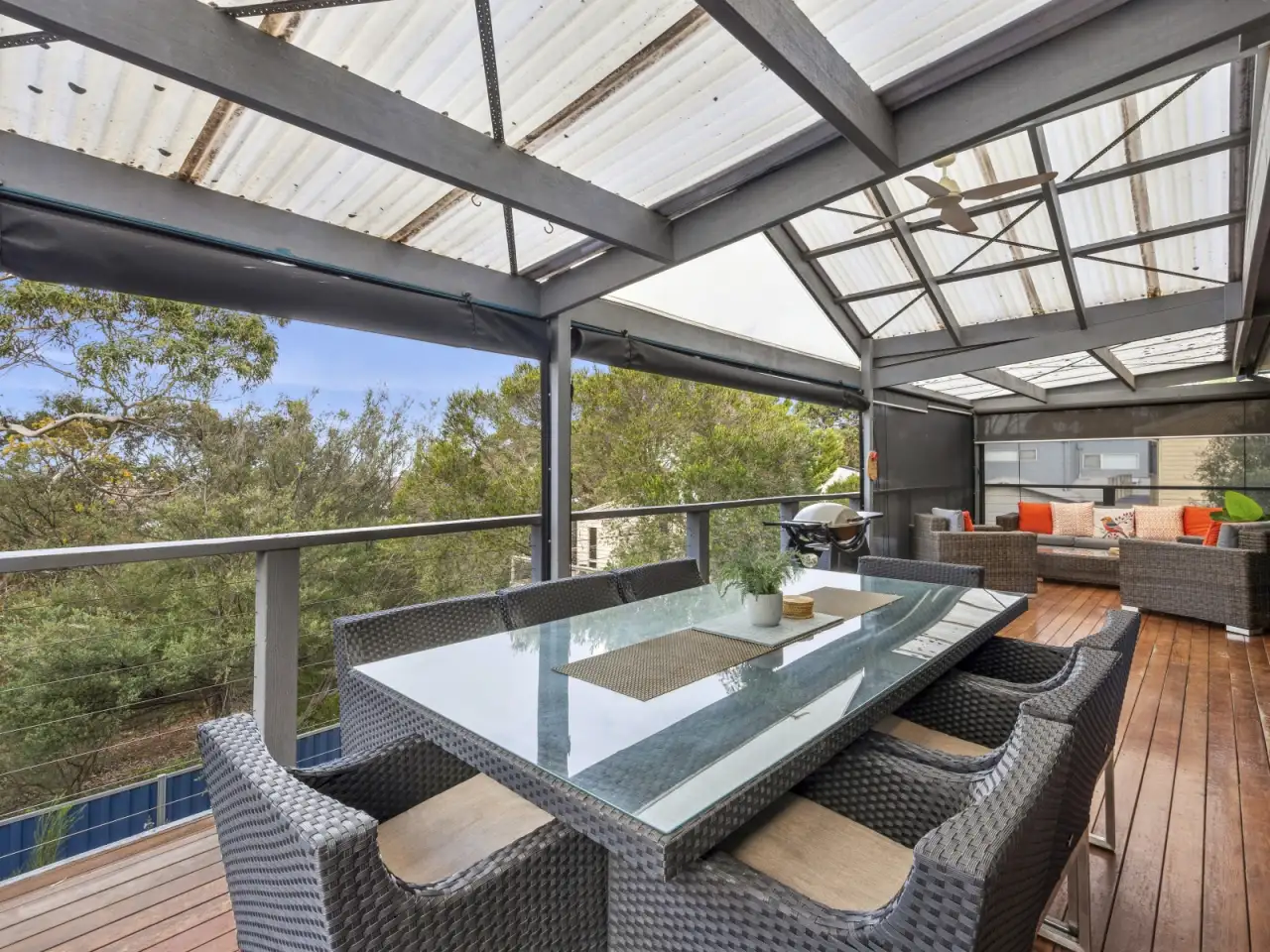 The large upstairs deck at Barrakee Beach House, set among gum trees