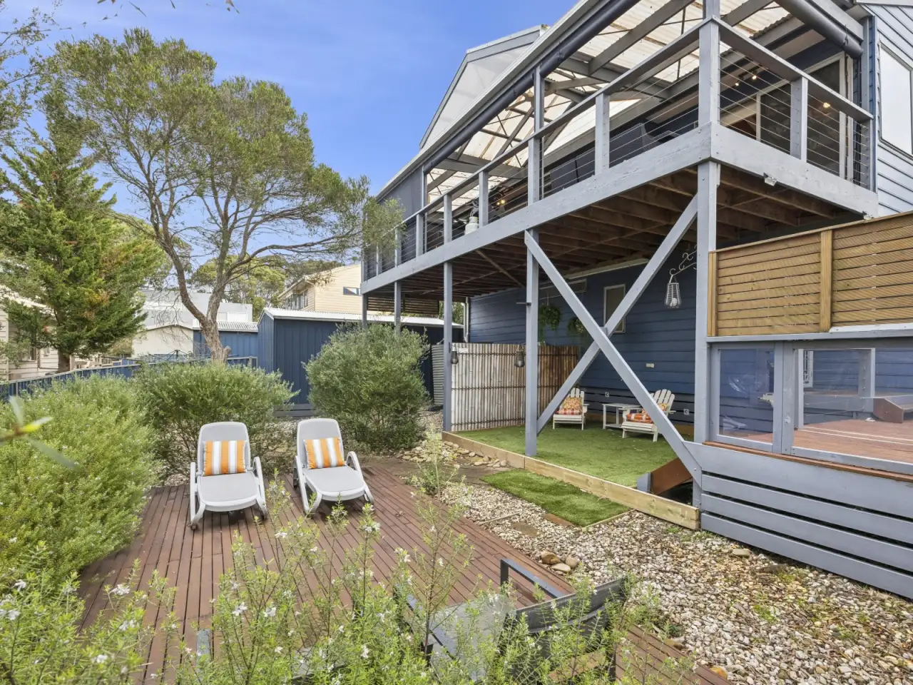 Sun loungers on the rear deck with the house and upstairs deck above